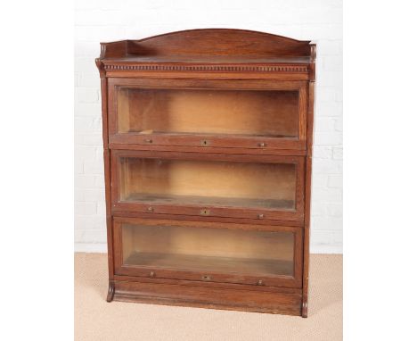 A 1930S LEBUS OAK THREE TIER SECTIONAL BOOKCASEwith arched gallery top and dentil frieze, the three sections with glazed risi