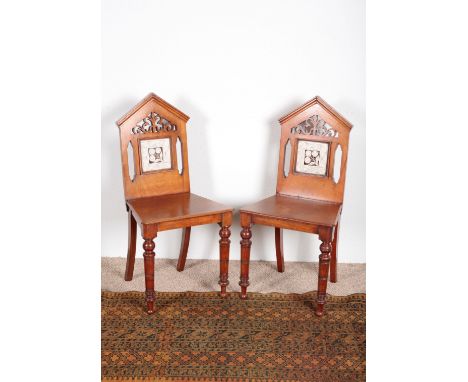 A PAIR OF VICTORIAN WALNUT HALL CHAIRSthe pierced back rests inset with tile panels, on turned front legs and outswept rear l