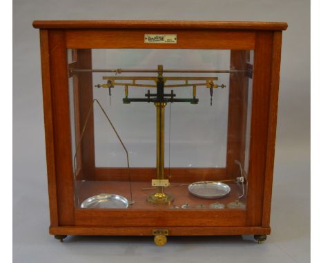 A set of Oetling, London scales housed within in a glazed mahogany case, 45cm x 44cm