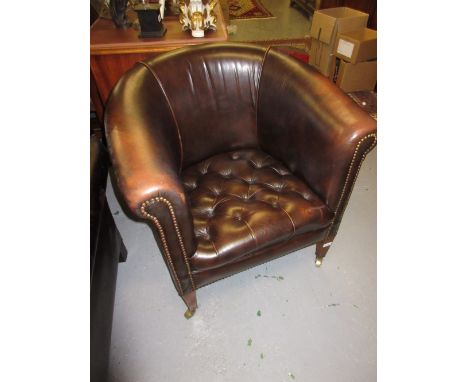 Edwardian brass studded leather tub chair with a button seat raised on square tapering mahogany supports with brass casters
