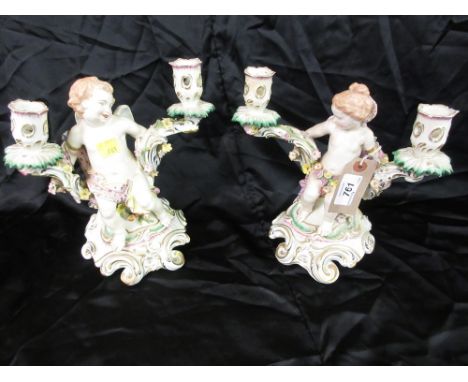 Pair of Continental porcelain twin light figural candle holders in the form of putti (slight damages), 9ins high approximatel