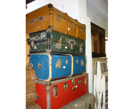 Three various vintage travelling trunks and suitcases and a modern metal bound red trunk