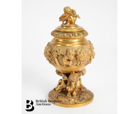 French gilt metal inkwell and cover, cast with animals and classical profiles, supported on a circular base, approx 15 cms h.
