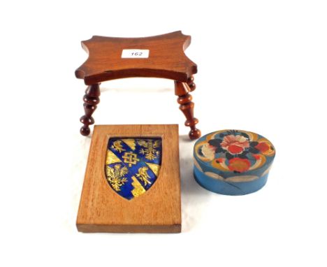 An antique wooden table candle stand, an oval painted wooden box plus enamel shield Coat of Arms