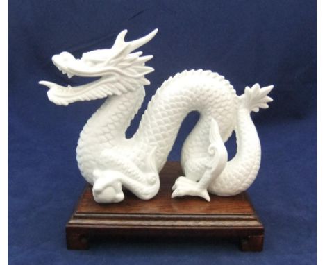 Finely detailed, white fired ceramic dragon (unmarked) on chinese wood plinth,21 cm long 