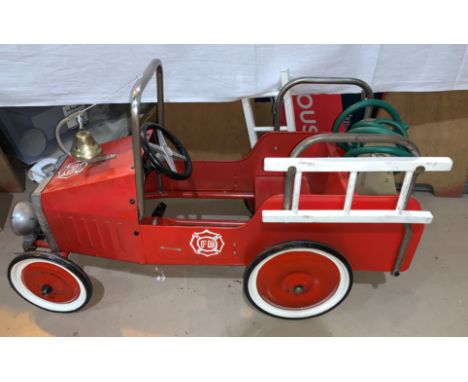 A child's vintage tinplate sit in and pedal red fire engine with bell and hose