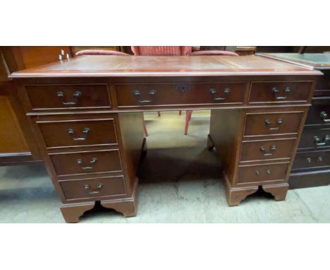 A reproduction yew pedestal desk, the leather inset top above a central drawer and two banks of four drawers on bracket feet