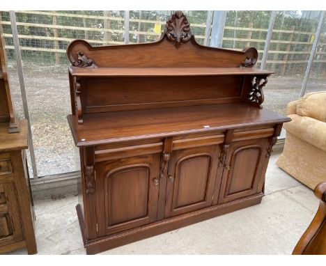 A MAHOGANY SIDEBOARD WITH THREE DOORS, THREE DRAWERS AND UPPER SPLASHBACK WITH SHELF AND CARVED SCROLL DECORATION 