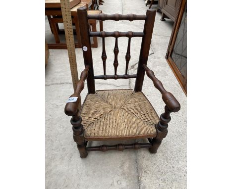 AN INFANTS MINIATURE OAK ARMCHAIR WITH RUSH SEAT 