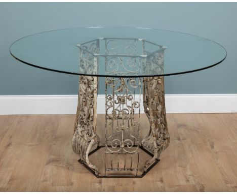 A circular dining or centre table The glass top on a painted hexagonal wrough iron base.130cm diameter x 79cm highQty: 1The g