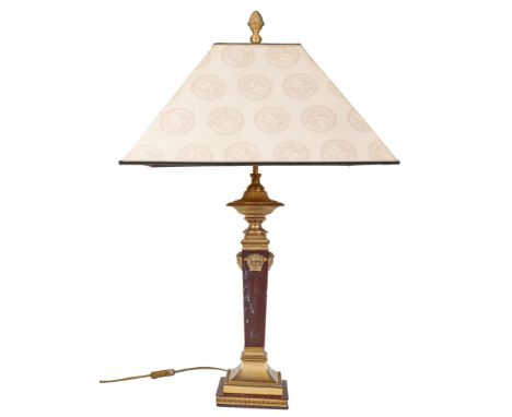 A Versace table lamp The table lamp with gilt metal mounts and Medusa masks applied to the square tapering marble column on a