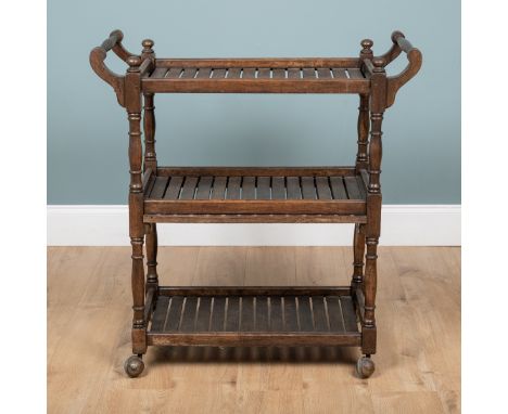 An early 20th century oak three-tier trolley With sled handles and turned supports raised on castors.91cm wide x 40cm deep x 