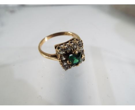 A 9ct yellow gold claw set Emerald and CZ cluster ring, comprising of a square Emerald 4.4mm ( synthetic) surrounded by 12 CZ