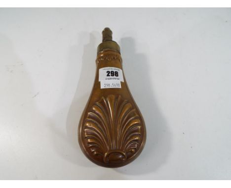 A copper powder flask, embossed on both sides with a shell pattern, spring top, graduated nozzle. Estimate £15 - £20