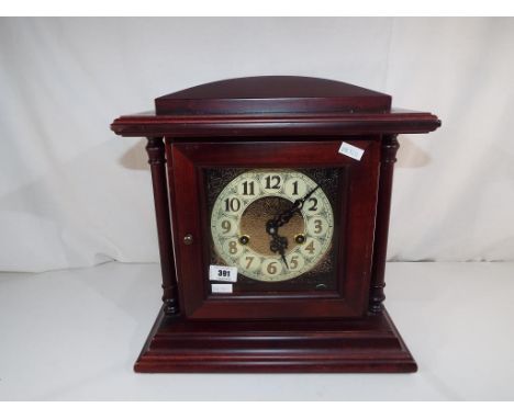 A modern mahogany cased mantel clock with Arabic numerals on a yellow metal dial with pendulum and keys. Estimate £20 - £40
