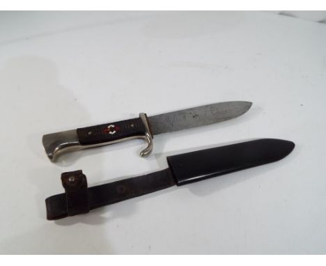 A Hitler Youth dagger with nickel plated pommel and crossguard. It has original black chequered grips, the front inset with t