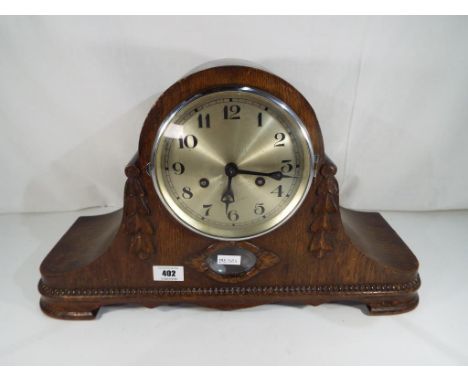 A highly carved oak cased mantel clock with pendulum and key, appears to be in working order although no guarantee. Estimate 