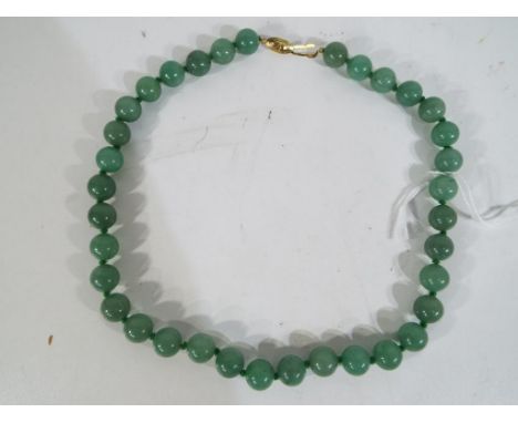 A green hardstone knotted beaded necklace (possible jade) 35 beads in total, approximately 48 cm in length, weight approximat