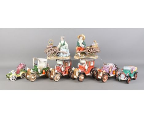 A quantity of ceramic cars and vehicles, two showing figures with carts as fruit sellers.