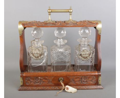 A late Victorian oak tantalus with three cut-glass decanters and silver-plated mounts, comes with key.  Height of the frame i