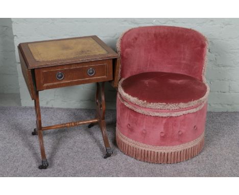 A small bedroom chair in pink velvet upholstery with a sofa style table with leather inset top