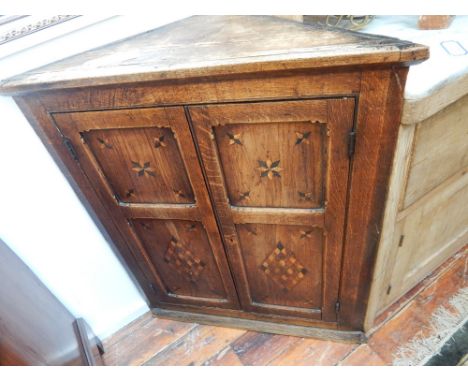 A George III oak corner cupboard, the multi-panel door with geometric inlay enclosing a shelved interior, W. 87cm.