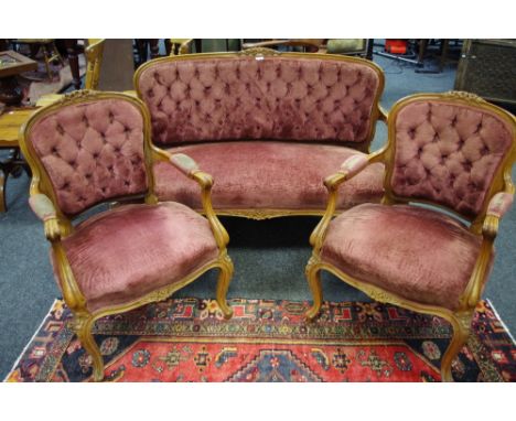 A satinwood salon suite comprising two seat sofa and two armchairs, button upholstered, floral carved cresting rails, French 