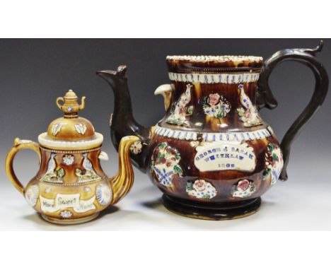 A large Edward VII barge ware teapot, decorated in relief with peacock and bouquet sprigs; another smaller 