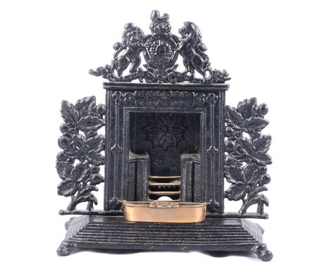 A small cast iron model of a fireplace, royal coat of arms to top, oak leaves and acorn decoration to either side, removeable