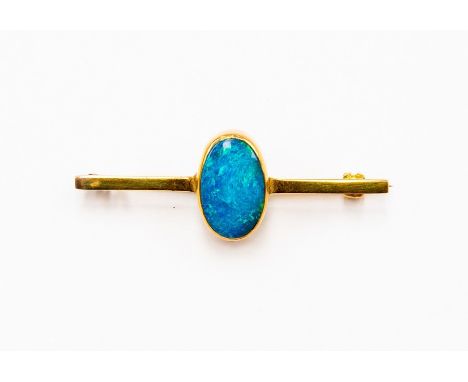 A black opal brooch, oval opal with blue and green play of colour, length approx14mm x 9mm, rub-over set in unmarked yellow m