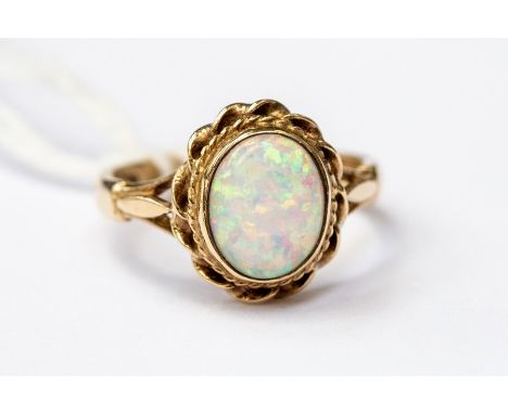 An opal dress ring, oval opal with a 9ct gold rope surround, opal with pink and green play of colour, size O, total gross wei