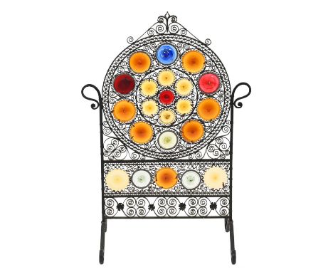 A black painted metal and coloured glass fire screen, 20th c, 84cm Complete, several elements becoming slightly loose