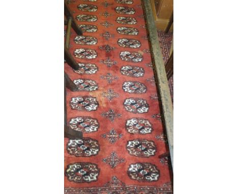 A Bokhara carpet, the repeating elephant foot medallions on terracotta ground within similarly decorated borders, 284 cm x 37