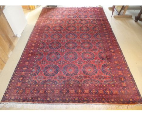 A Bokhara carpet, the central ground with repeating diamond and star shaped motifs in red, black, orange and cream within sim