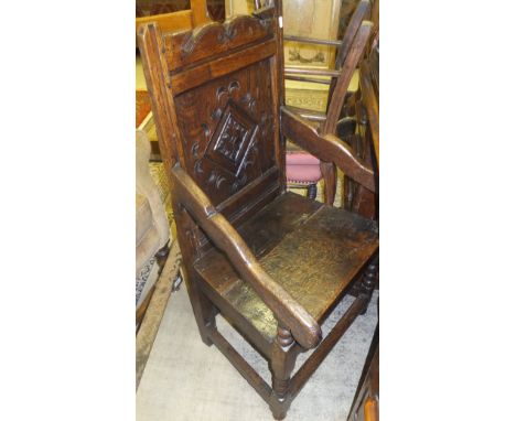 An oak Wainscott style dining carver chair with carved panel back in the form of a diamond and two plank seat raised on bobbi