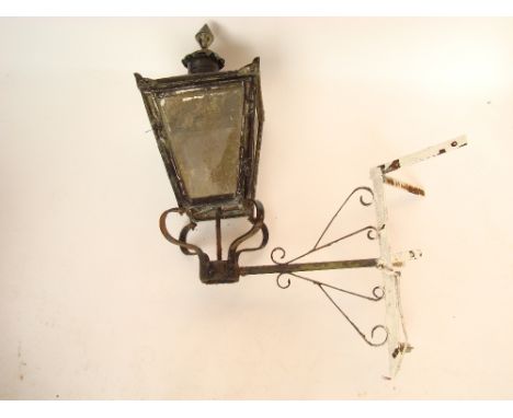 A late 19th Century black painted copper lantern, with hinged side door, mounted on wrought iron corner wall bracket, approx 