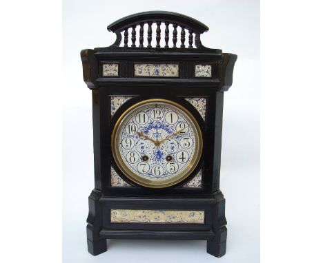 A large aesthetic movement ebonised cased mantel clock, the circular porcelain dial painted in blue with Arabic numerals and 