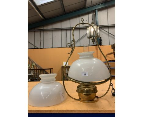 A DECORATIVE BRASS OIL LAMP WITH AN OPAQUE GLASS SHADE AND HANGING HANDLE.  TO INCLUDE A SPARE SHADE 