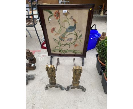 TWO BRASS AND IRON LION FIRE DOGS AND AN EMBROIDERED PEACOCK FIRE SCREEN 