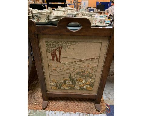 A HAND EMBROIDERED FIRESCREEN ON A WOODEN STAND 