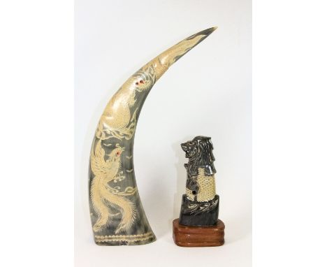 An oriental dragon head decorated carved horn sword hilt mounted on a wooden base together with a decorated horn.