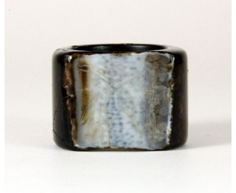 An unusual Chinese carved brown and white jade archers ring with a flattened and engraved white panel W.2.5cm
