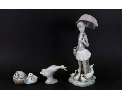A Lladro figure of a girl with an umbrella and two figures of ducks