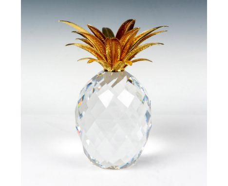 A clear crystal pineapple with square texture cuts and fronds that are designed in a gold-color. Swarovski backstamp. This it