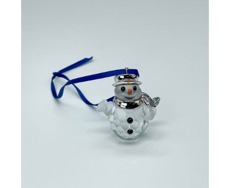 A charming snowman crafted in clear crystal, featuring a rhodium hat and scarf, adorned with black buttons and an orange carr
