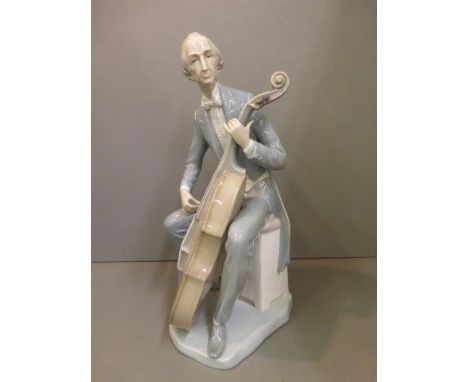 A Lladro figure of a seated musician playing a cello.