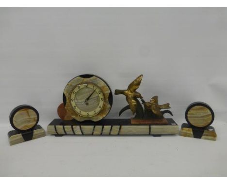 An Art Deco marble and onyx clock garniture, the clock surmounted by two birds in flight, with converted movement. 