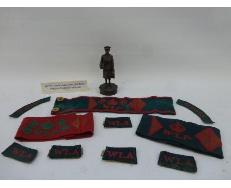 A collection of women's Land Army arm bands and patch badges; also a carved figure of a lady dressed in uniform. 