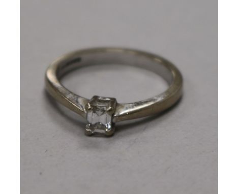 A modern 18ct white gold and solitaire emerald cut diamond ring, size M.