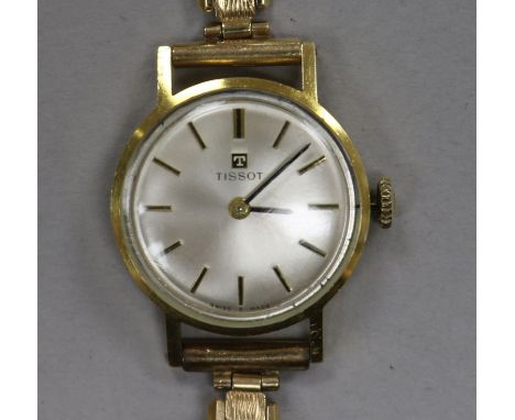 A lady's yellow metal Tissot manual wind wrist watch on a 9ct gold bracelet.